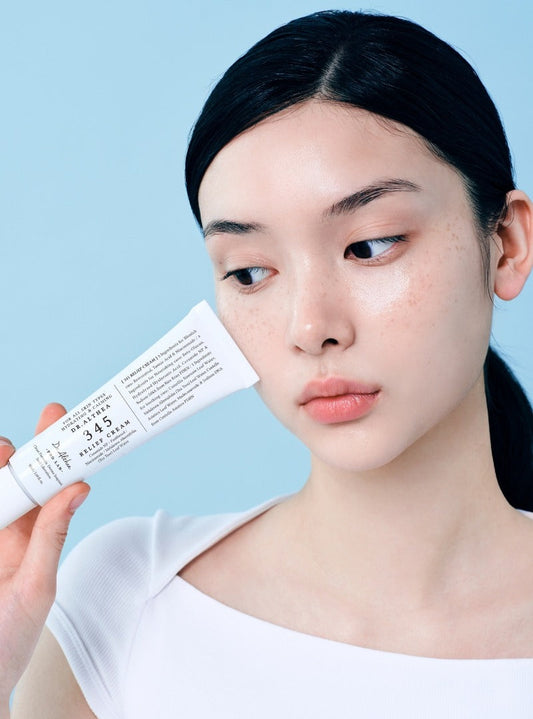 Woman holding a 345 cream against a light blue background
