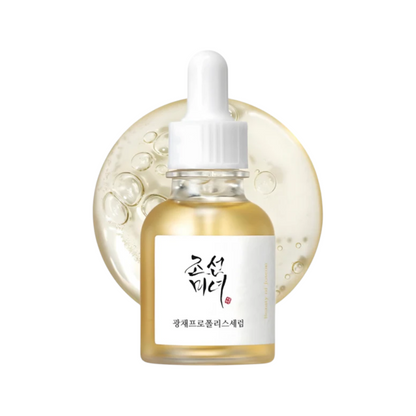 A small clear glass dropper Beauty of Joseon Glow Serum: Propolis + Niacinamide 30ml filled with pale golden liquid, centered in front of a translucent circular gel swatch on a white background. The bottle has a white dropper cap and a white label with black Korean text and a small red mark.