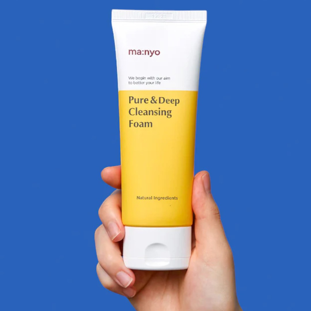 ma:nyo Pure&Deep Cleansing Foam 200ml in hand on a blue background, showcasing natural ingredients.