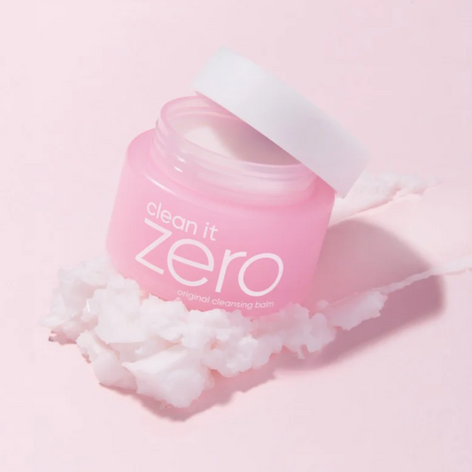 Pink jar of Clean It Zero Exfoliating Cleansing Balm with white lid, shown on a pink background with white exfoliating balm residue.