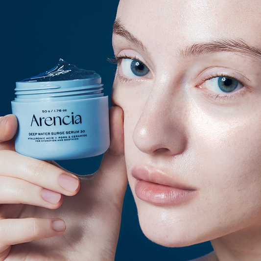 Person holding a jar of Arencia Deep Water Surge Serum 30 against a blue background