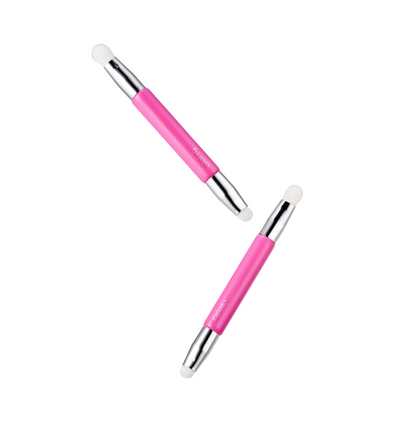 Two pink and silver dual-ended facial cleansing brushes floating diagonally on a light gray background.