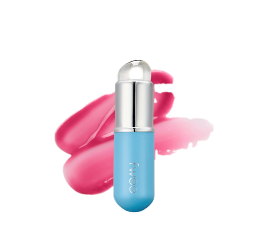 A light blue cosmetic stick with a silver cap and clear dome tip, shown in front of pink and pink-peach swatches on a plain white background. The vertical brand name 'fwoa' is printed on the tube.
