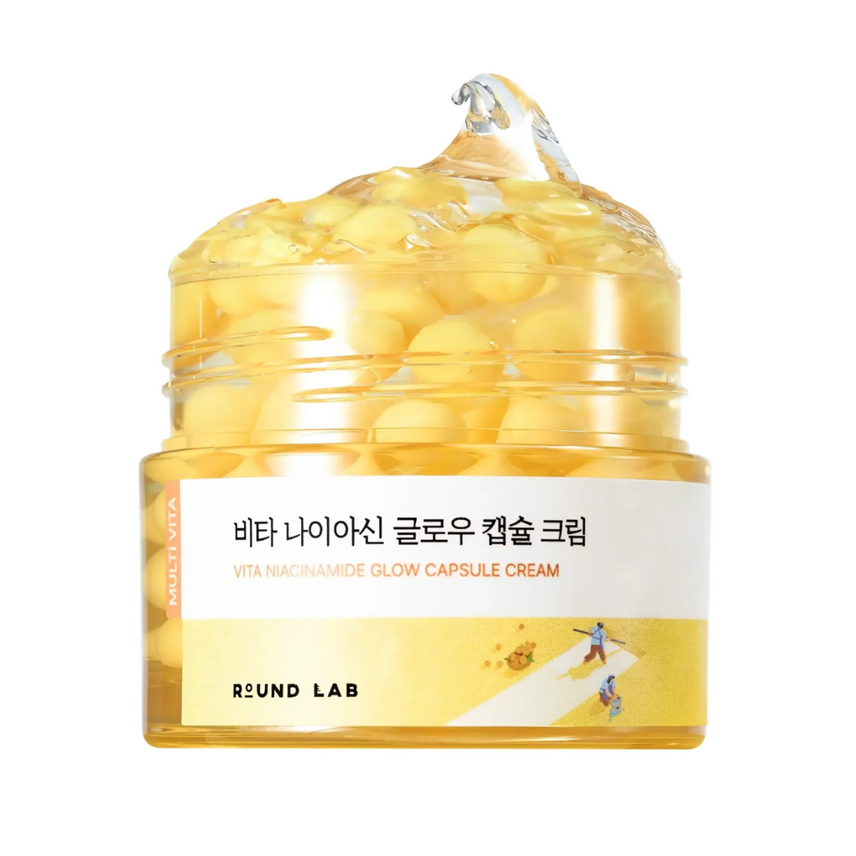 A clear cosmetic jar filled with yellow gel and large yellow capsules, with a white and yellow label reading 'VITA MACHAMIDE GLOW CAPSULE CREAM' and 'ROUND LAB'.