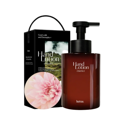 Hetras Hand Lotion Essence bomshell in a dark amber pump bottle next to its black gift box with a pink flower graphic, on a clean white background.