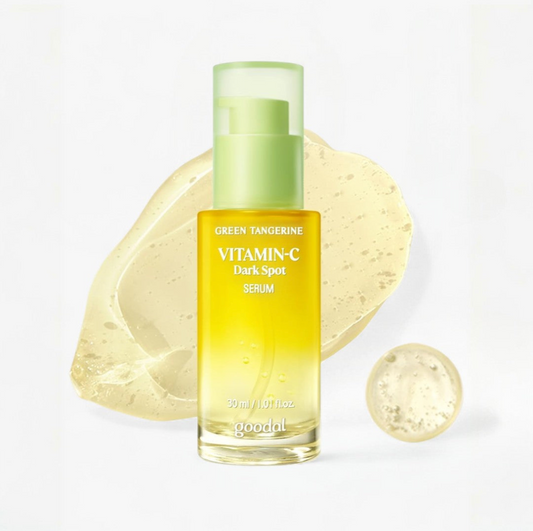 Goodal Green Tangerine Vitamin-C Dark Spot Serum in a clear bottle with a light green pump, shown on a white background with a translucent yellow serum smear and droplet behind it.