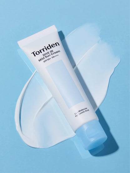 A tube of Torriden Dive In Mild Sun Cream SPF 50+ lies diagonally on a light blue background with a white cream smear behind it.
